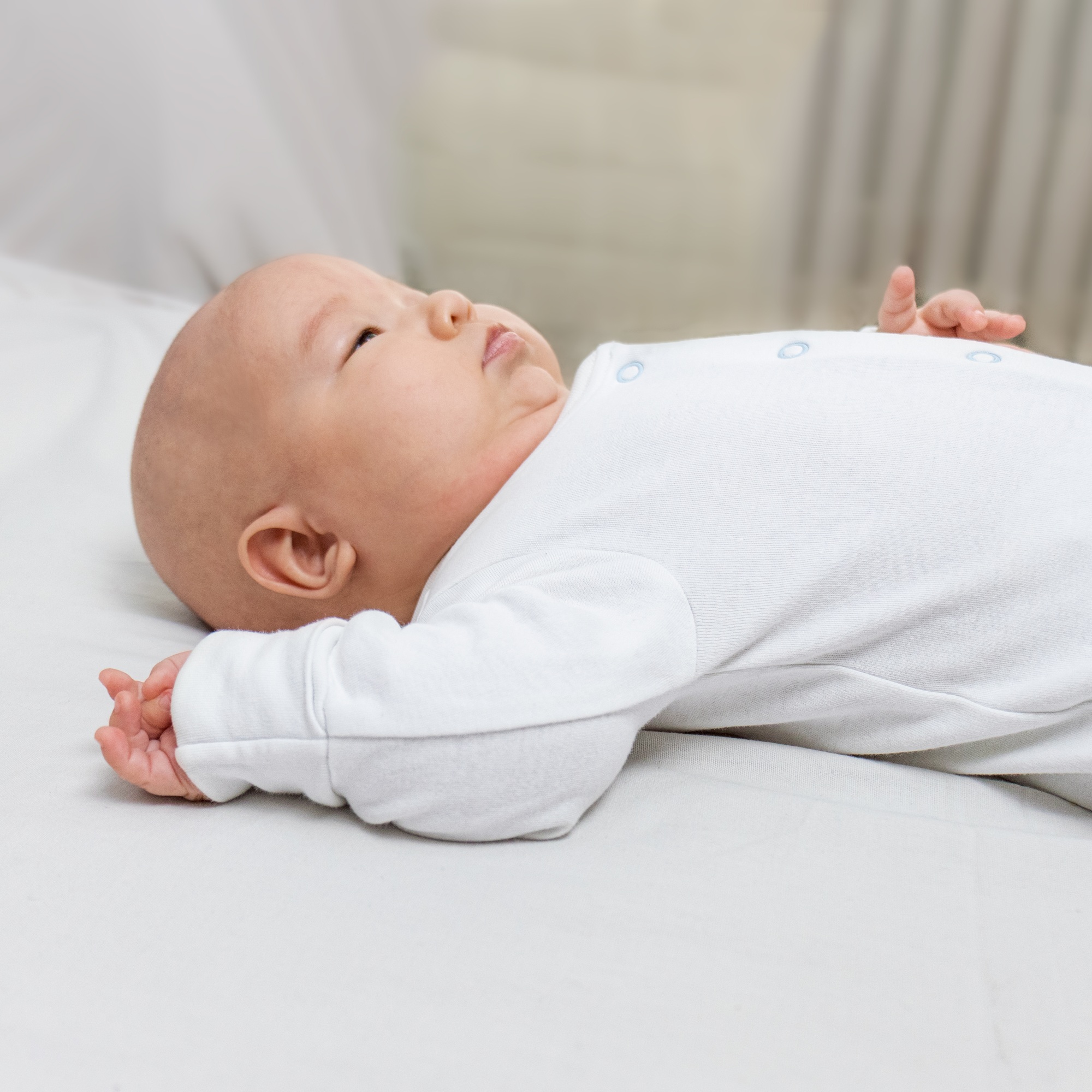 asian baby in white clothes lies on the bed and looks up. selective focus.family.at home