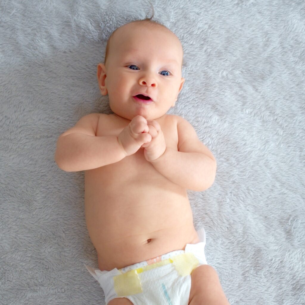 Cute baby with blue eyes. Happy newborn boy lies on a blue blanket