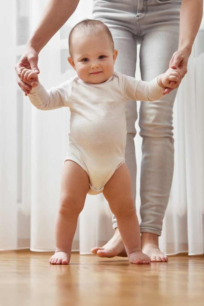 happy little baby girl learning to walk with mother help